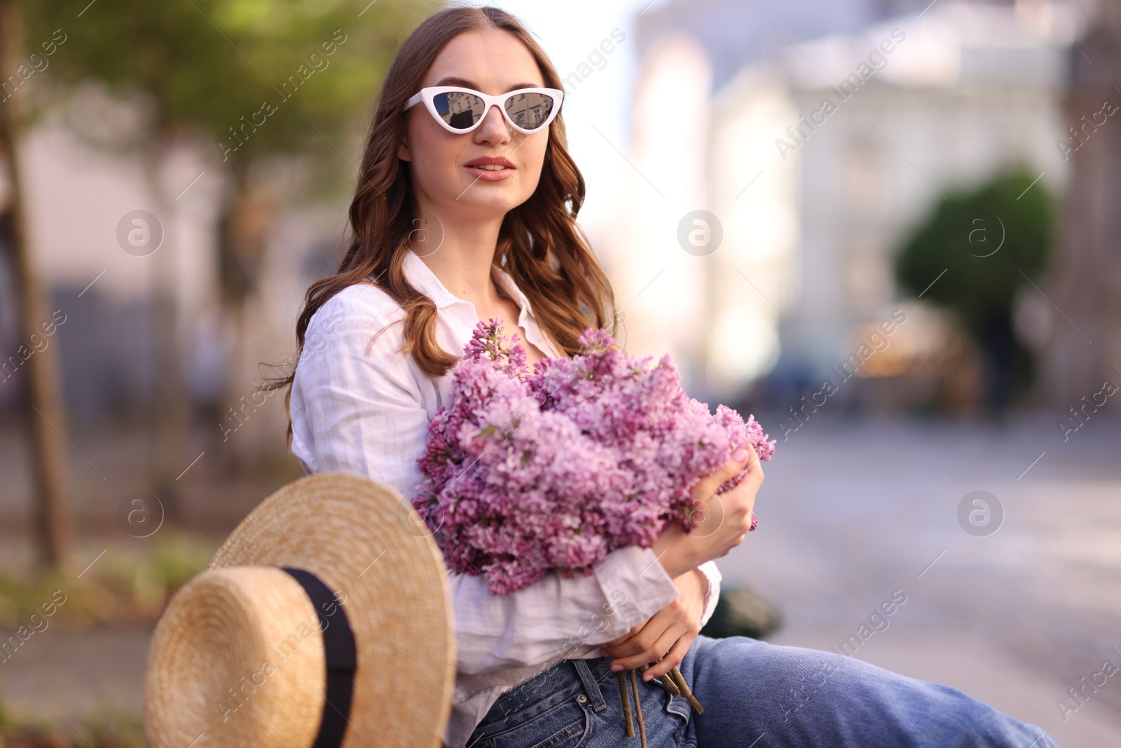 Beautiful woman in sunglasses with bouquet of lilac flowers outdoors Photo of Beautiful woman in sunglasses with bouquet of lilac flowers outdoors