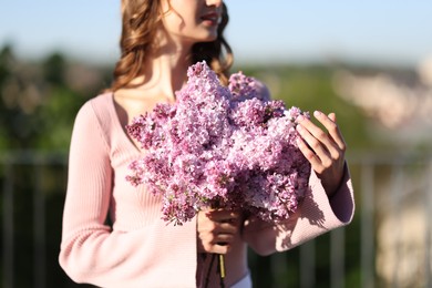 Photo of Woman with bouquet of lilac flowers outdoors in morning, selective focus