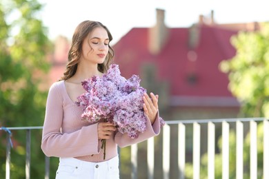 Photo of Beautiful woman with bouquet of lilac flowers outdoors in morning. Space for text