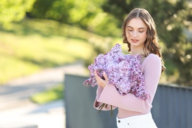 Photo of Beautiful woman with bouquet of lilac flowers outdoors in morning. Space for text