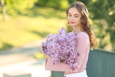 Photo of Beautiful woman with bouquet of lilac flowers outdoors in morning. Space for text