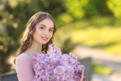 Photo of Smiling woman with bouquet of lilac flowers outdoors in morning. Space for text