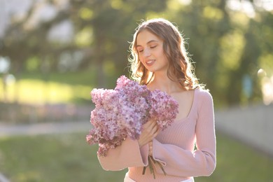 Photo of Smiling woman with bouquet of lilac flowers outdoors in morning