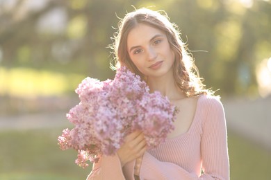 Photo of Portrait of beautiful woman with bouquet of lilac flowers outdoors in morning