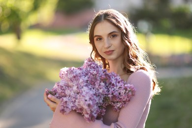 Photo of Portrait of beautiful woman with bouquet of lilac flowers outdoors in morning