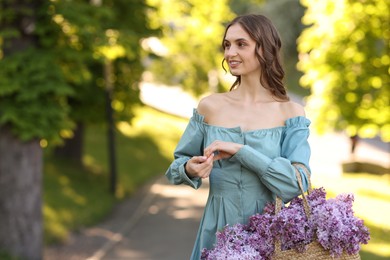 Photo of Smiling woman with bag of lilac flowers outdoors in morning. Space for text
