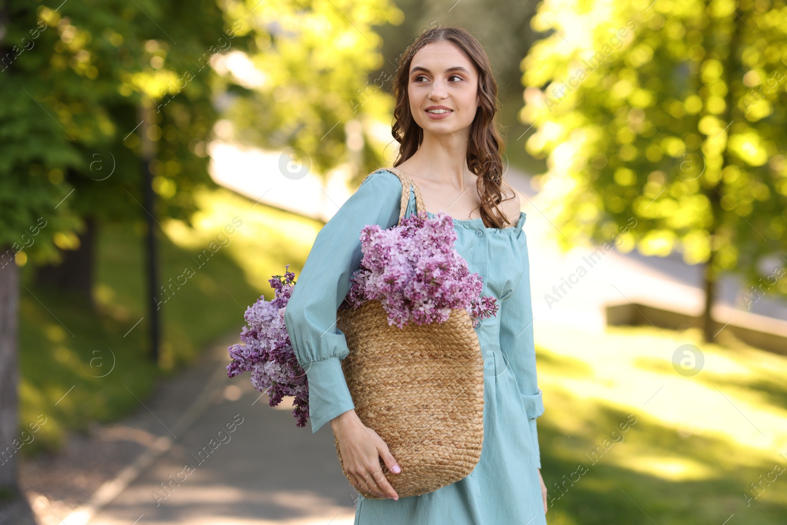 Smiling woman with bag of lilac flowers outdoors in morning Photo of Smiling woman with bag of lilac flowers outdoors in morning