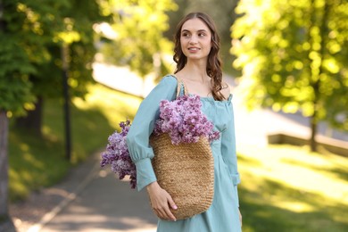 Photo of Smiling woman with bag of lilac flowers outdoors in morning