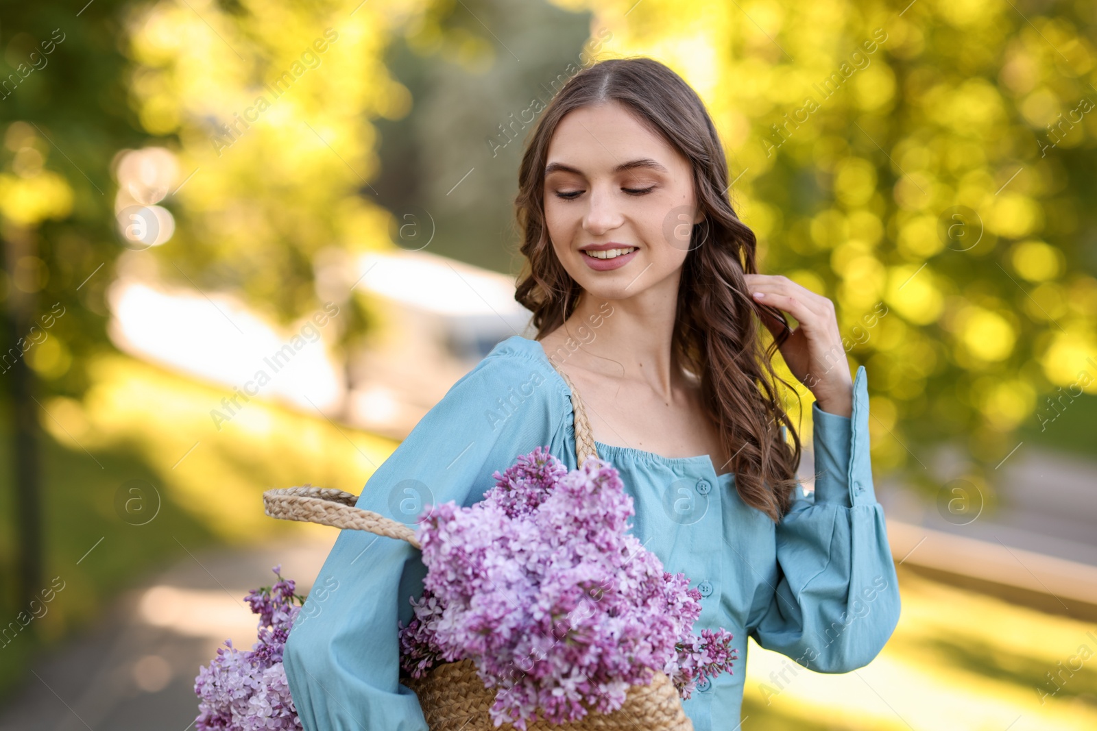 Smiling woman with bag of lilac flowers outdoors in morning Photo of Smiling woman with bag of lilac flowers outdoors in morning