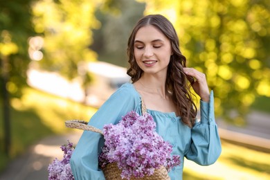 Photo of Smiling woman with bag of lilac flowers outdoors in morning