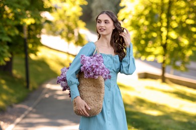 Photo of Smiling woman with bag of lilac flowers outdoors in morning