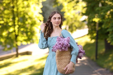 Photo of Smiling woman with bag of lilac flowers outdoors in morning