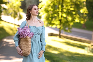 Photo of Smiling woman with bag of lilac flowers outdoors in morning. Space for text
