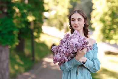 Photo of Smiling woman with bouquet of lilac flowers outdoors in morning. Space for text