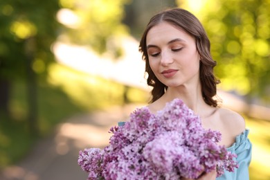 Photo of Beautiful woman with bouquet of lilac flowers outdoors in morning. Space for text