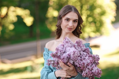 Photo of Beautiful woman with bouquet of lilac flowers outdoors in morning. Space for text