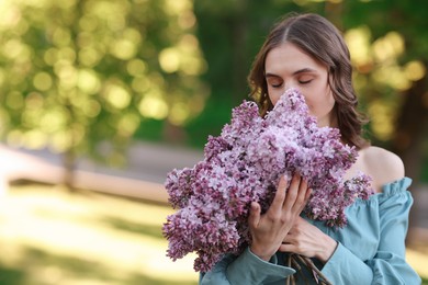 Photo of Beautiful woman with bouquet of lilac flowers outdoors in morning. Space for text