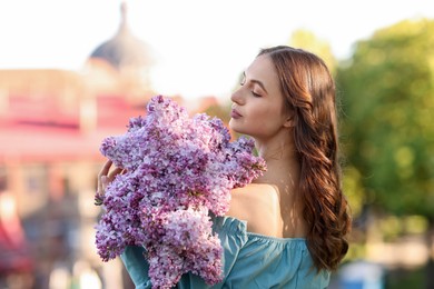 Photo of Beautiful woman with bouquet of lilac flowers outdoors in morning