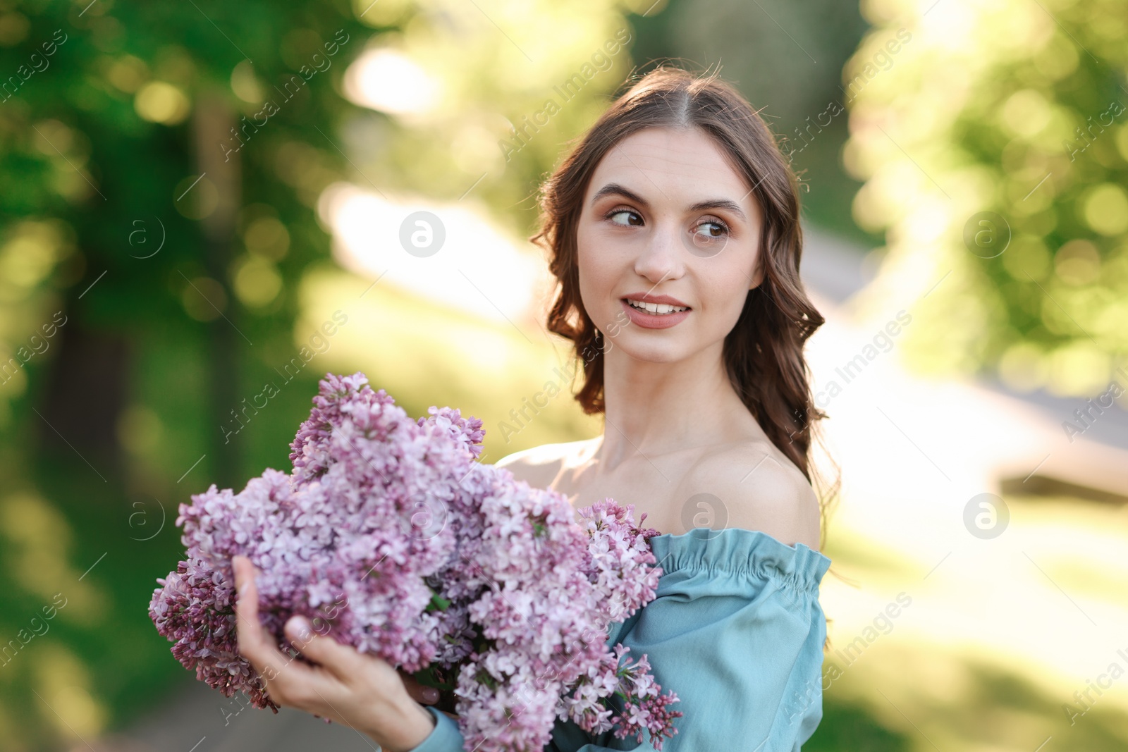 Smiling woman with bouquet of lilac flowers outdoors in morning Photo of Smiling woman with bouquet of lilac flowers outdoors in morning
