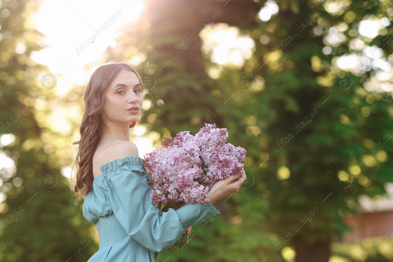 Beautiful woman with bouquet of lilac flowers outdoors in morning. Space for text Photo of Beautiful woman with bouquet of lilac flowers outdoors in morning. Space for text