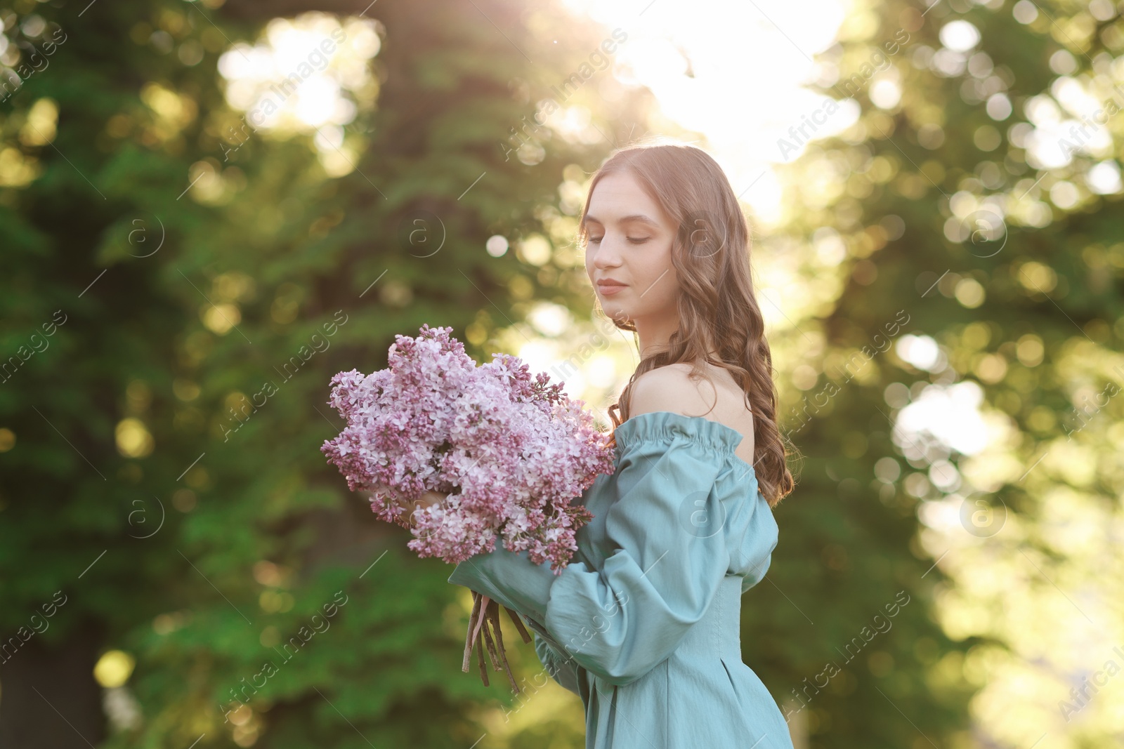 Beautiful woman with bouquet of lilac flowers outdoors in morning Photo of Beautiful woman with bouquet of lilac flowers outdoors in morning