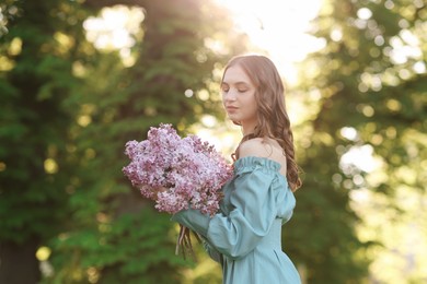 Photo of Beautiful woman with bouquet of lilac flowers outdoors in morning