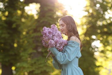Photo of Beautiful woman with bouquet of lilac flowers outdoors in morning. Space for text