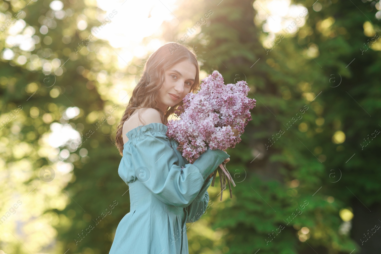 Beautiful woman with bouquet of lilac flowers outdoors in morning Photo of Beautiful woman with bouquet of lilac flowers outdoors in morning