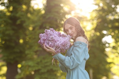 Photo of Beautiful woman with bouquet of lilac flowers outdoors in morning. Space for text