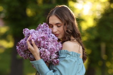 Photo of Beautiful woman with bouquet of lilac flowers outdoors
