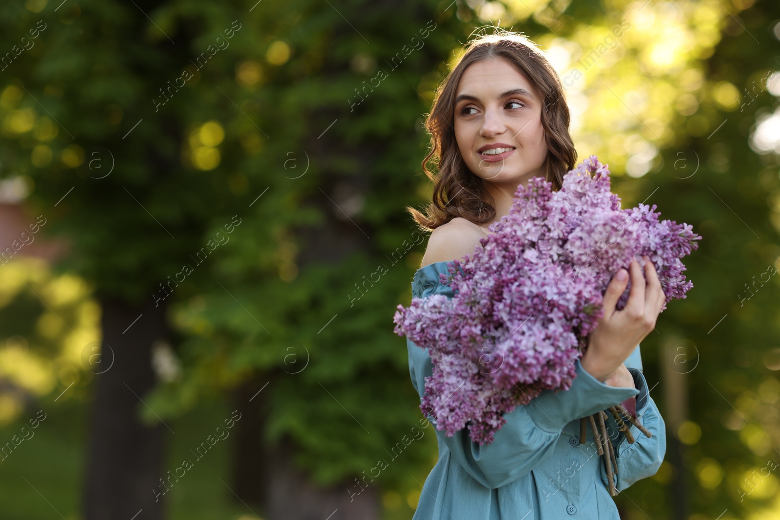 Smiling woman with bouquet of lilac flowers outdoors in morning. Space for text Photo of Smiling woman with bouquet of lilac flowers outdoors in morning. Space for text