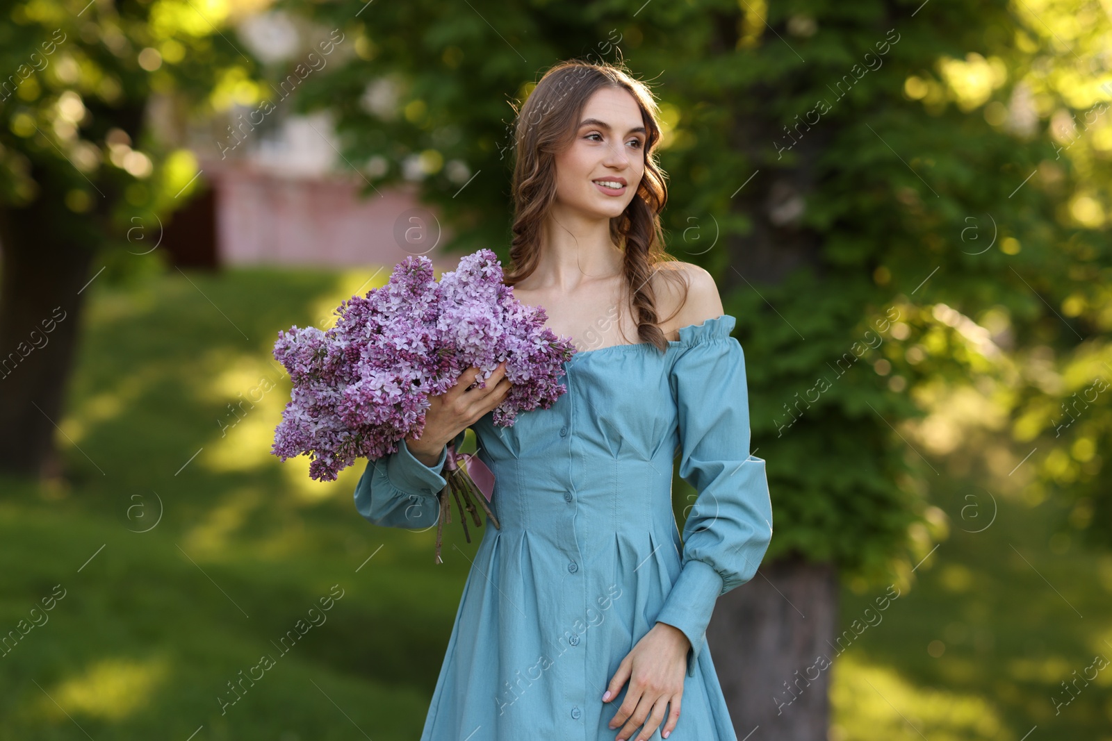 Smiling woman with bouquet of lilac flowers outdoors Photo of Smiling woman with bouquet of lilac flowers outdoors