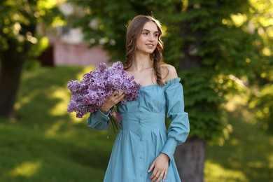 Photo of Smiling woman with bouquet of lilac flowers outdoors