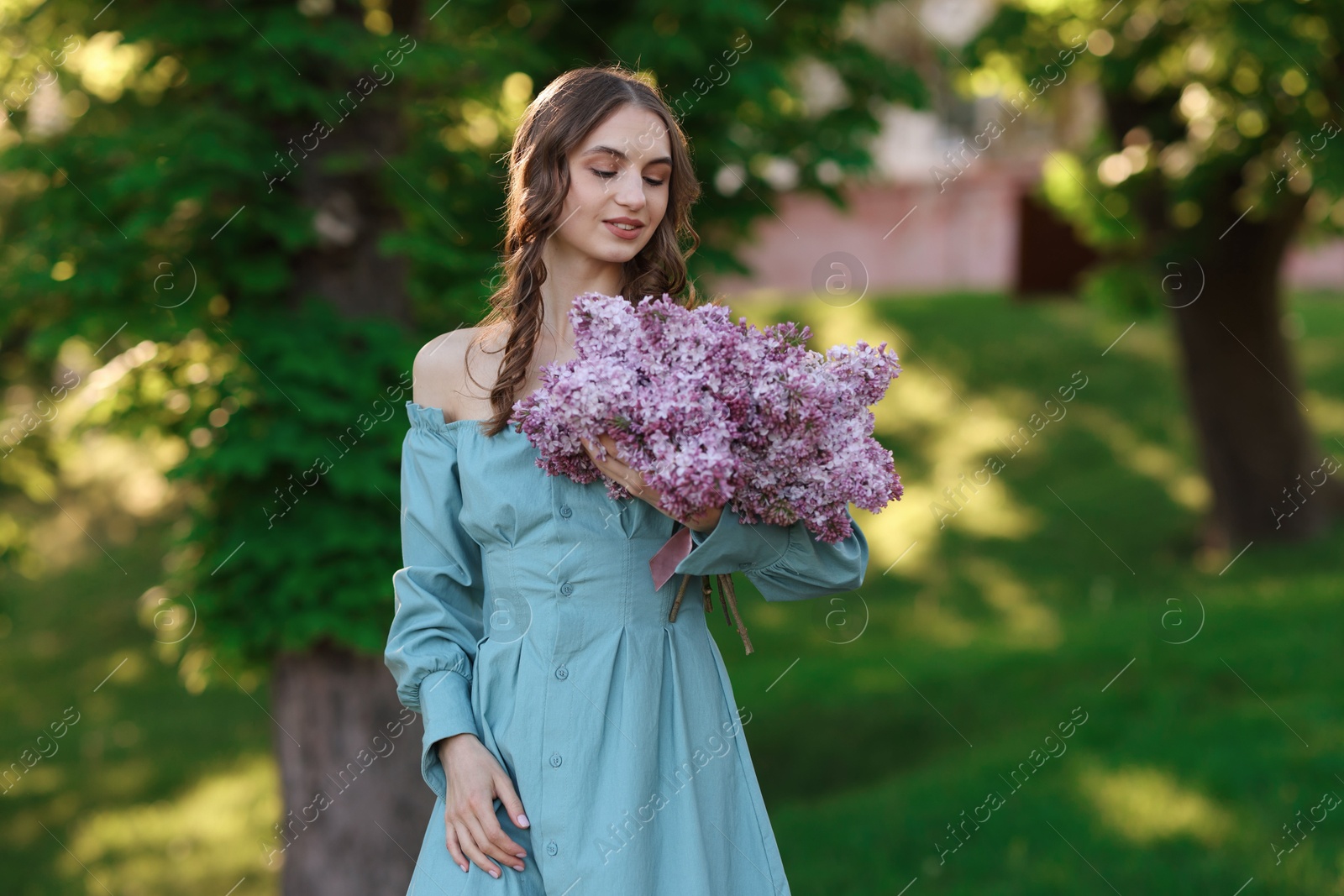 Smiling woman with bouquet of lilac flowers outdoors Photo of Smiling woman with bouquet of lilac flowers outdoors