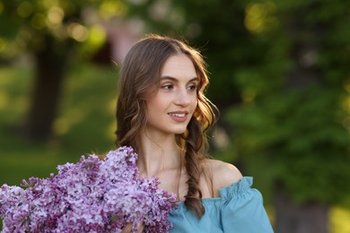 Photo of Smiling woman with bouquet of lilac flowers outdoors