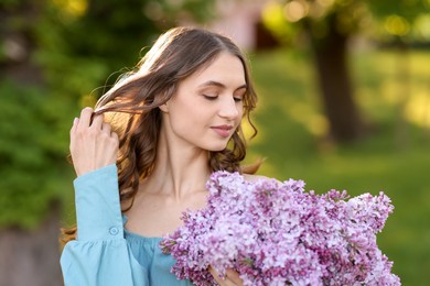 Photo of Smiling woman with bouquet of lilac flowers outdoors