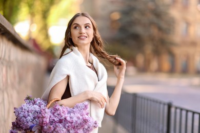 Photo of Smiling woman with basket of lilac flowers on city street