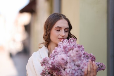 Photo of Beautiful woman with bouquet of lilac flowers on blurred background