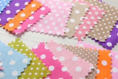 Photo of Samples of different fabrics on white wooden table, closeup