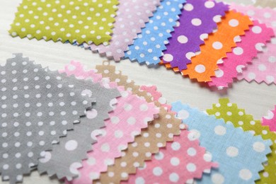 Photo of Samples of different fabrics on white wooden table, closeup