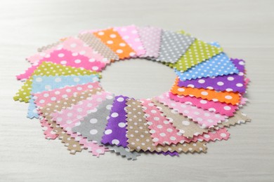 Photo of Samples of different fabrics on white wooden table, closeup