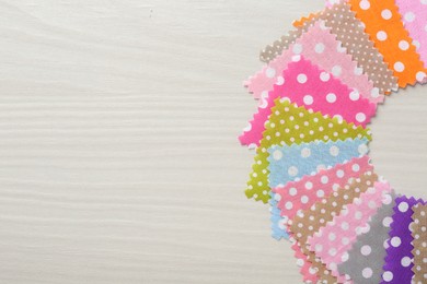 Photo of Samples of different fabrics on white wooden table, flat lay. Space for text