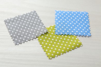 Photo of Samples of different fabrics on white wooden table, closeup