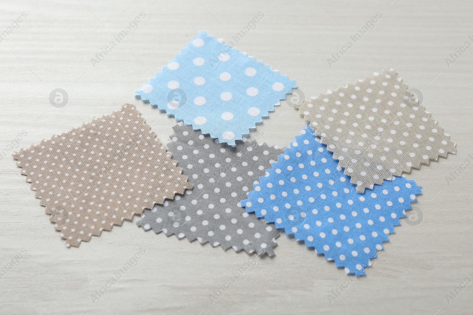 Samples of different fabrics on white wooden table, closeup Photo of Samples of different fabrics on white wooden table, closeup