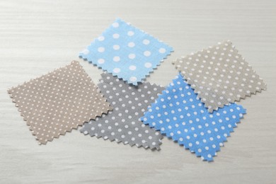 Photo of Samples of different fabrics on white wooden table, closeup