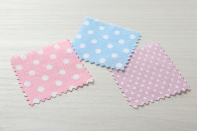 Photo of Samples of different fabrics on white wooden table, closeup