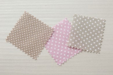 Photo of Samples of different fabrics on white wooden table, flat lay