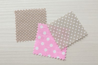 Photo of Samples of different fabrics on white wooden table, flat lay
