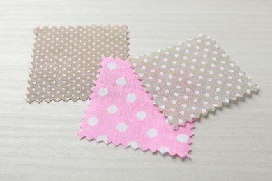 Photo of Samples of different fabrics on white wooden table, closeup