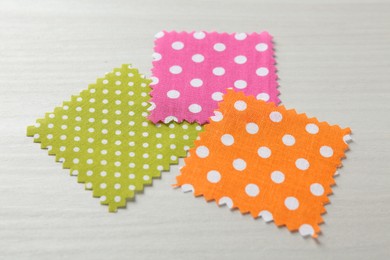 Photo of Samples of different fabrics on white wooden table, closeup